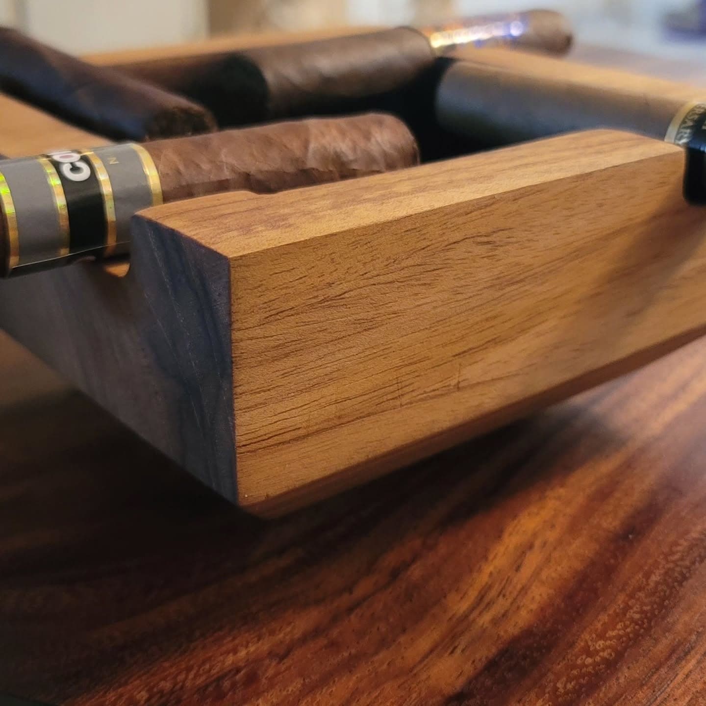 Heritage American Woodworks: a solid hardwood cigar ashtray holding four cigars, on a figured slab table top