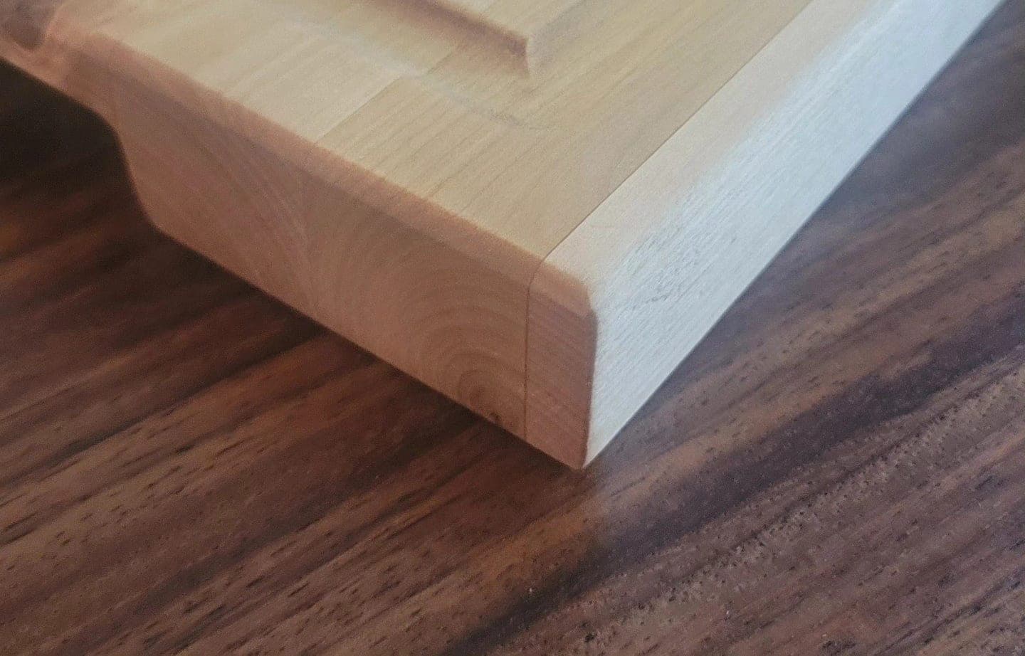 Heritage American Woodworks: a maple butcher block cutting board with a chamfered edge on a walnut surface