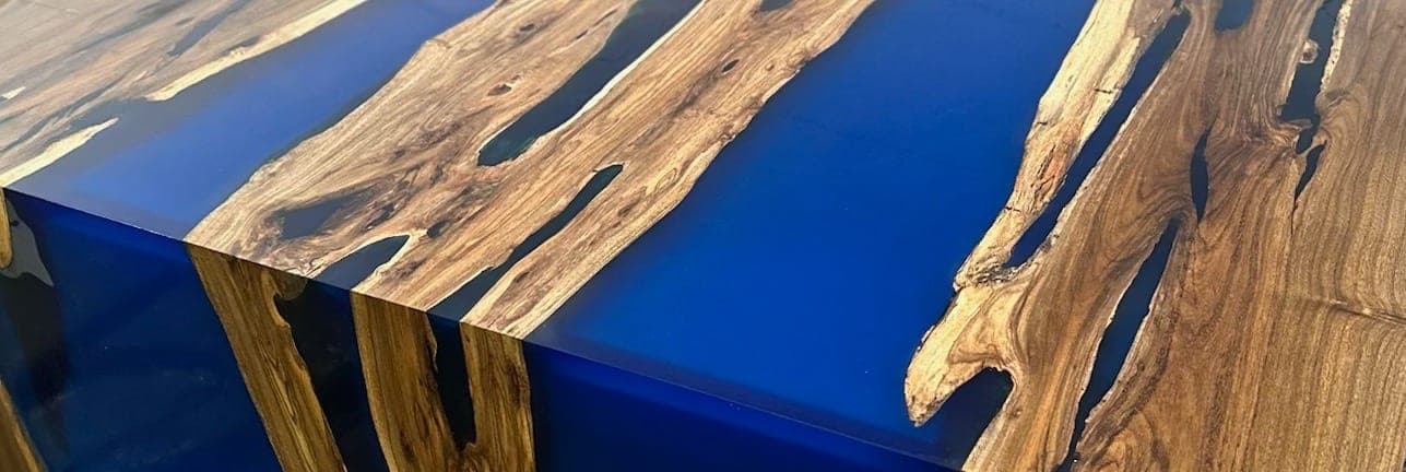 Heritage American Woodworks: a blue epoxy river running through a hardwood top and over a waterfall edge