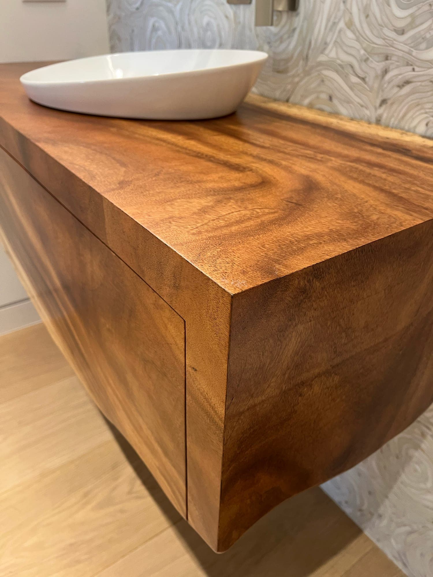 Heritage American Woodworks: the mitred corner of a floating hardwood vanity, the grain running unbroken around it