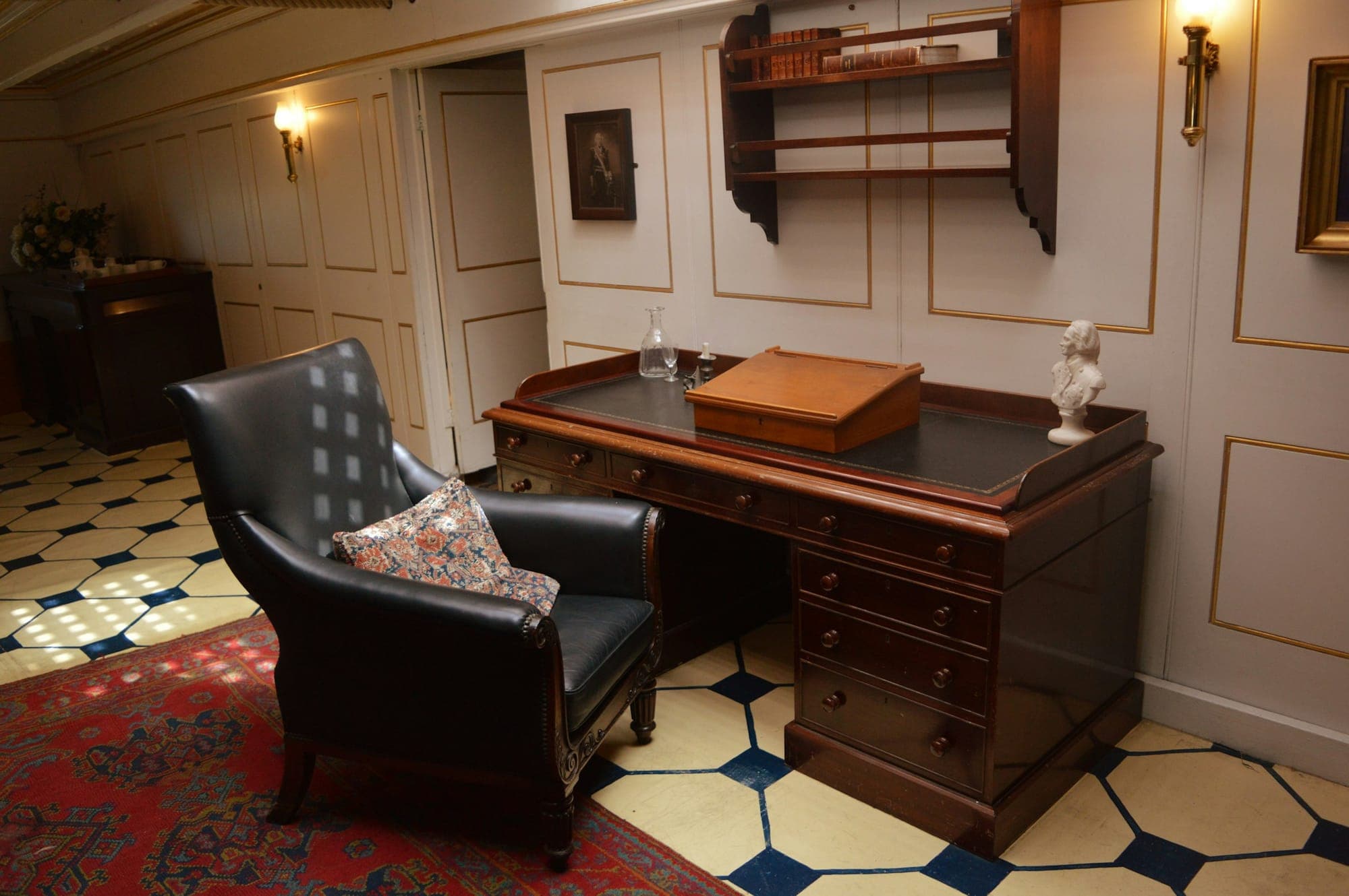 A weighty pedestal desk and leather armchair in a paneled study