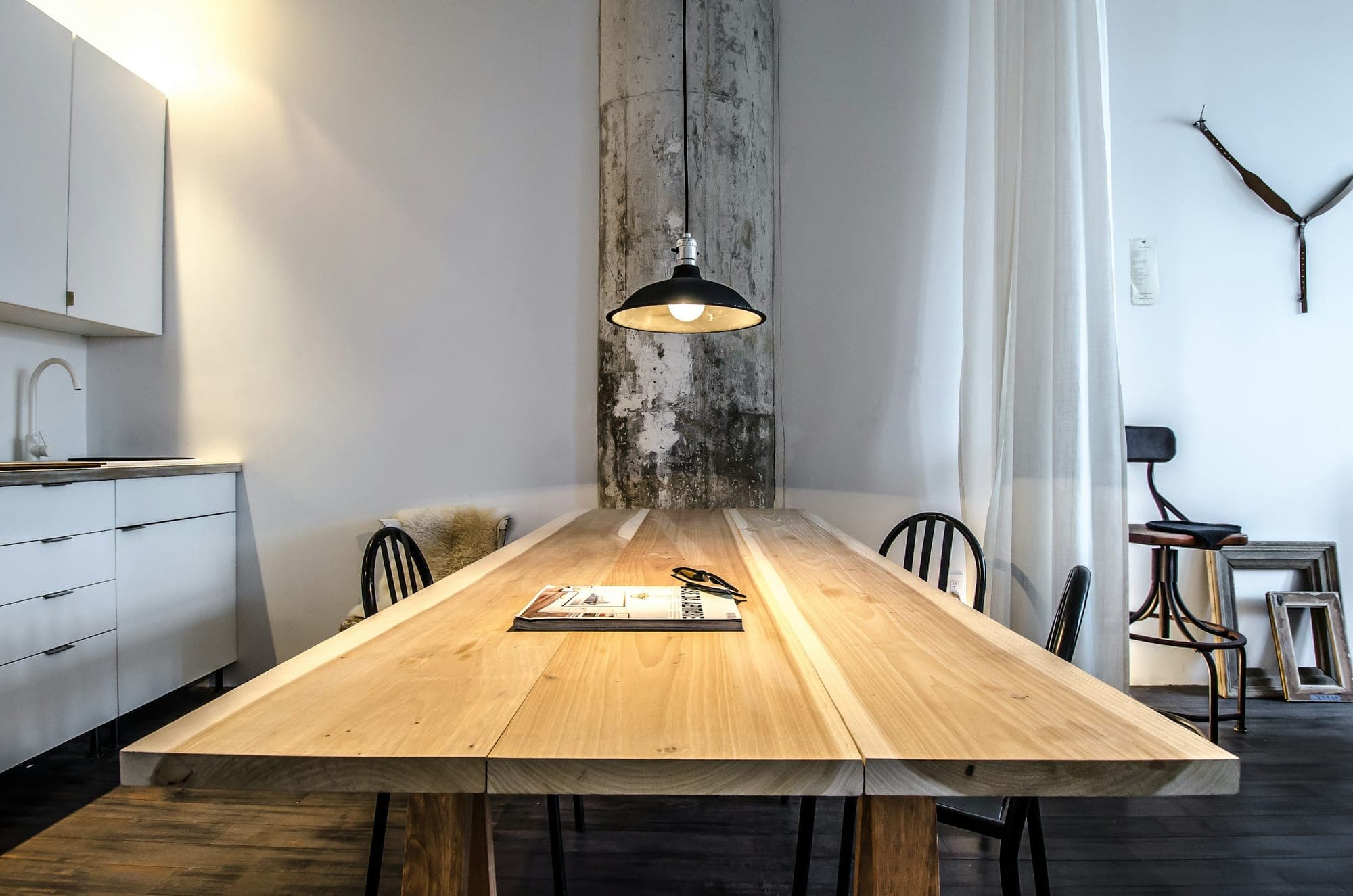 A live-edge slab dining table running the length of a white kitchen
