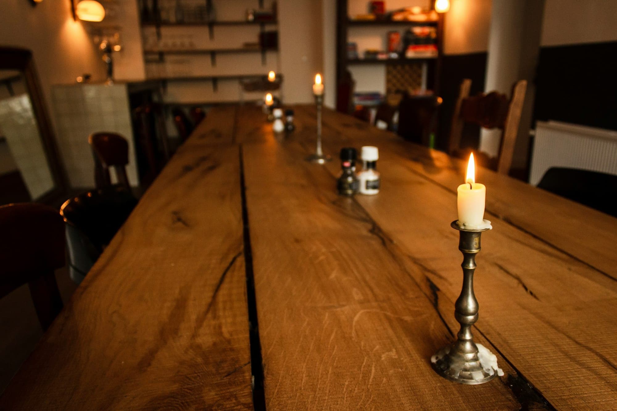 Thick oak planks of a long table top, candlelit